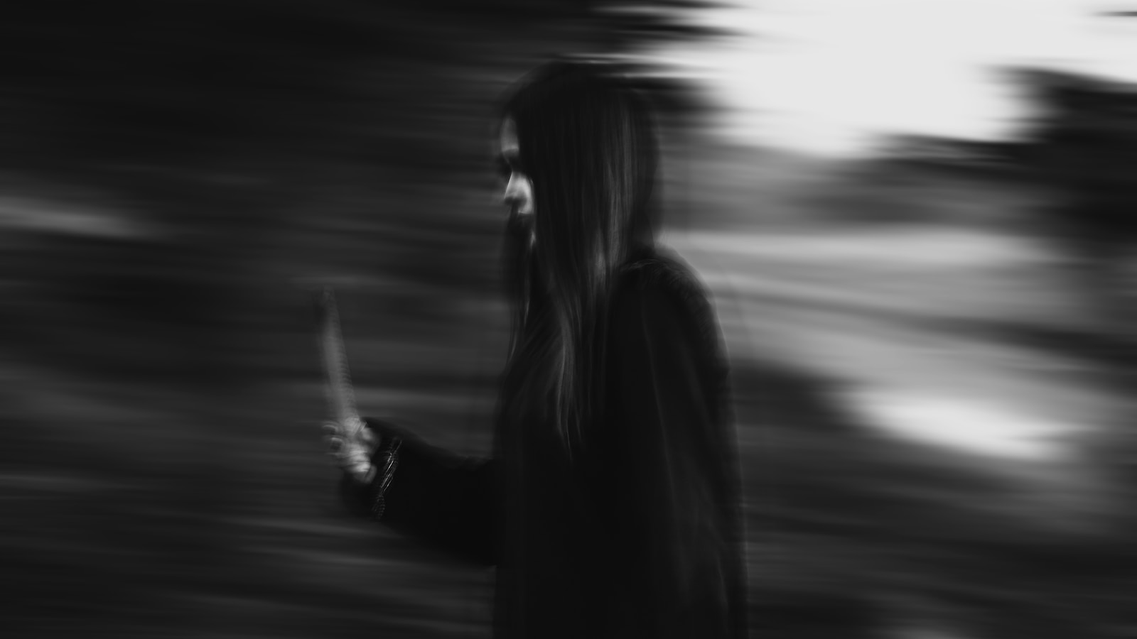 woman in black coat standing on road during daytime